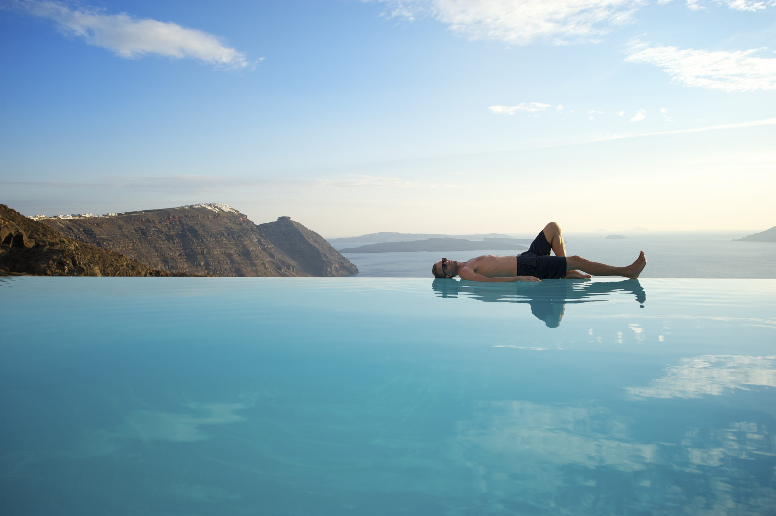 Man on infinity pool edge in Santorini, Greece